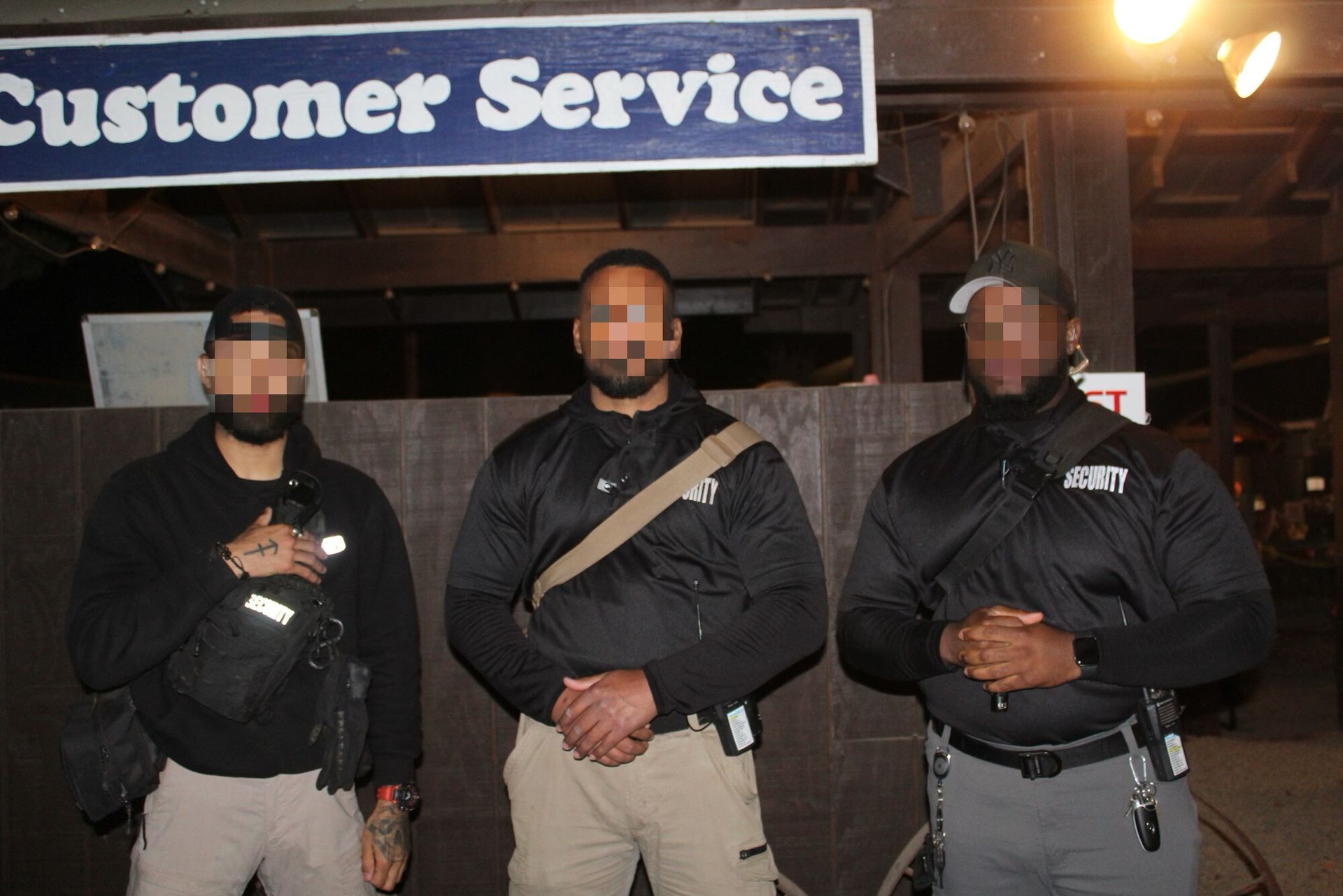 Three security guards stand in front of a 