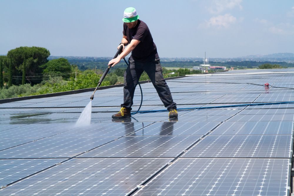 Person in Safety Gear Power-washing Solar Panels on a Rooftop — Busy Bees Blasting in Trinity Beach, QLD