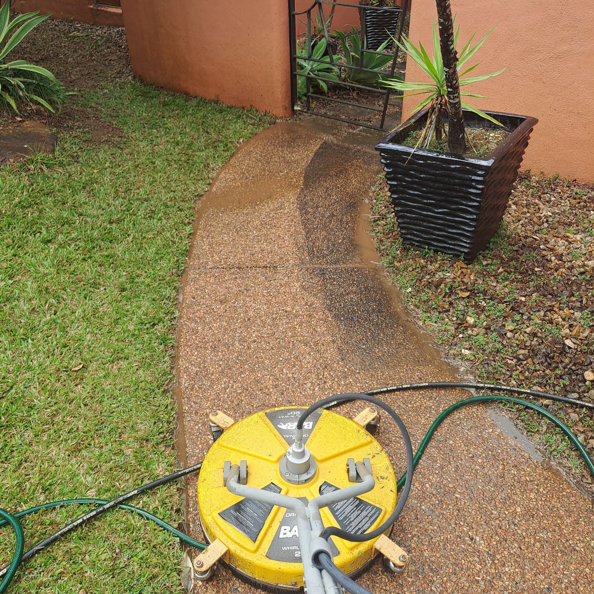 A person pressure washing a stone walkway with a yellow circular cleaner — Busy Bees Blasting in Trinity Beach, QLD