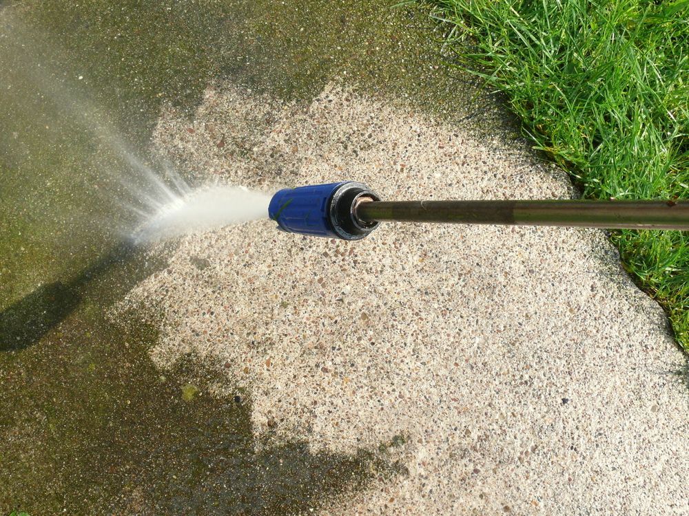 Pressure Washer Spraying Water Onto Concrete — Busy Bees Blasting in Trinity Beach, QLD