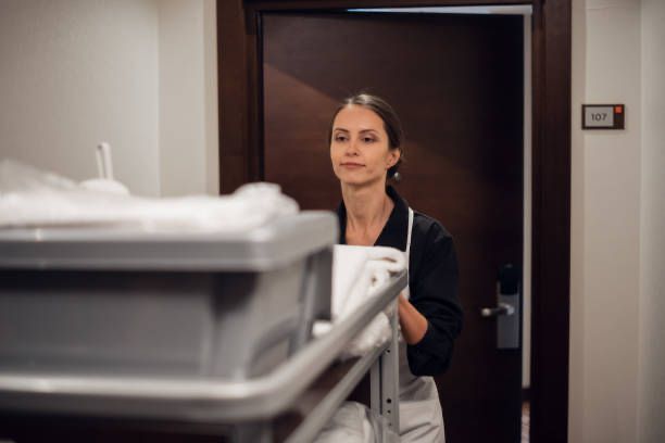 Eine Person reinigt einen Schreibtisch mit einem Tuch und einer Sprühflasche.