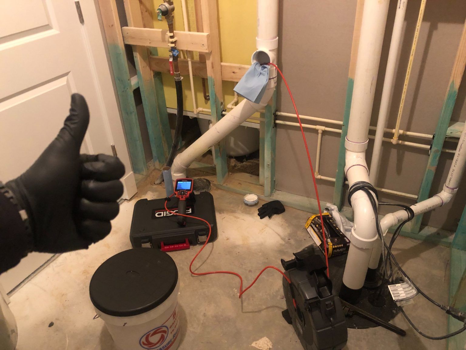 A person is giving a thumbs up in a room with pipes.