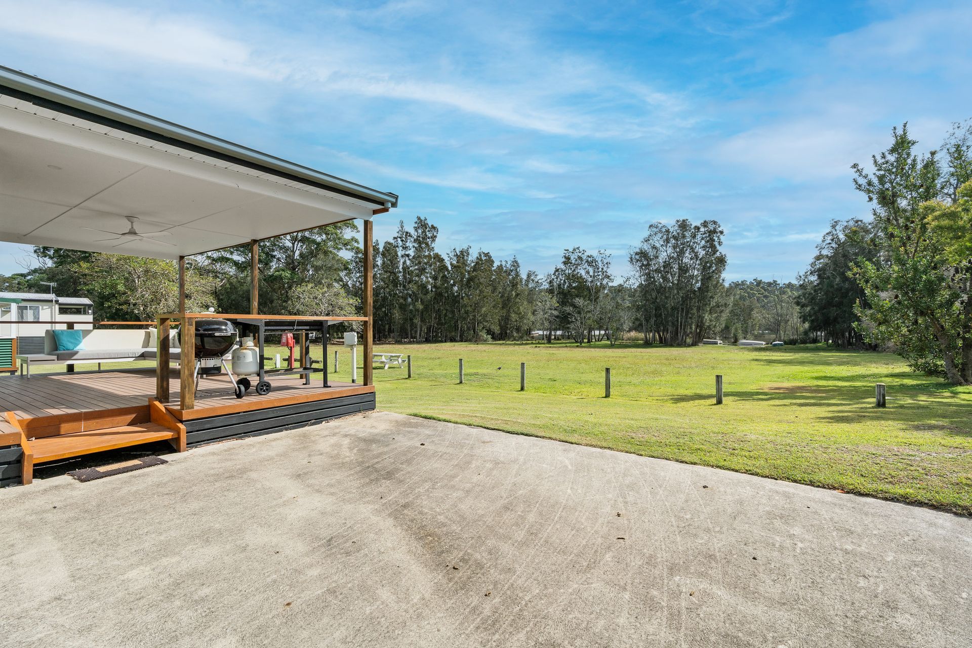 Covered patio overlooking a grassy field with trees under a blue sky — SeaChange Parks Milton in Lake Conjola, NSW