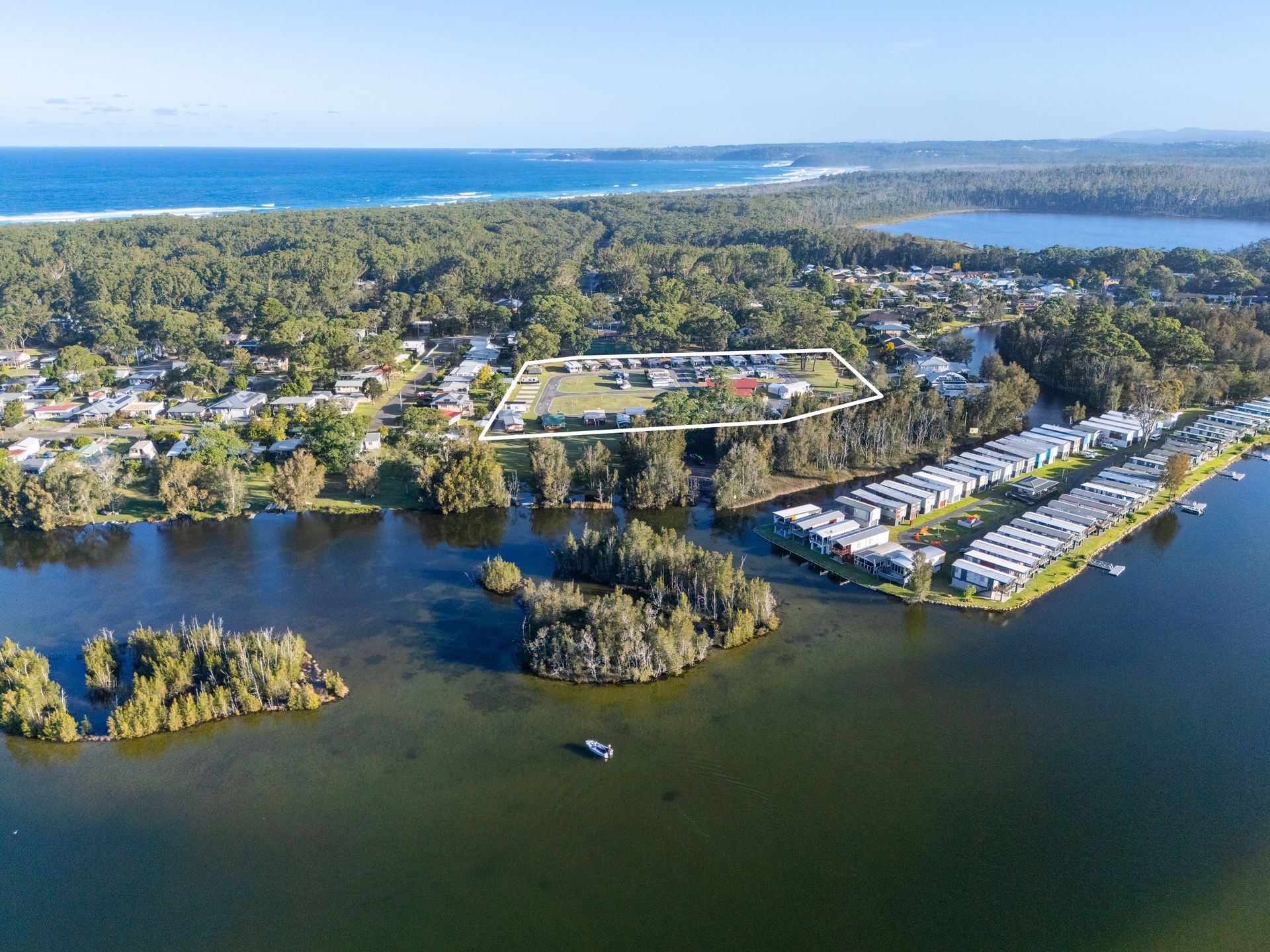 Aerial view of a coastal town with a lake in the foreground, outlining a property — SeaChange Parks Milton in Lake Conjola, NSW