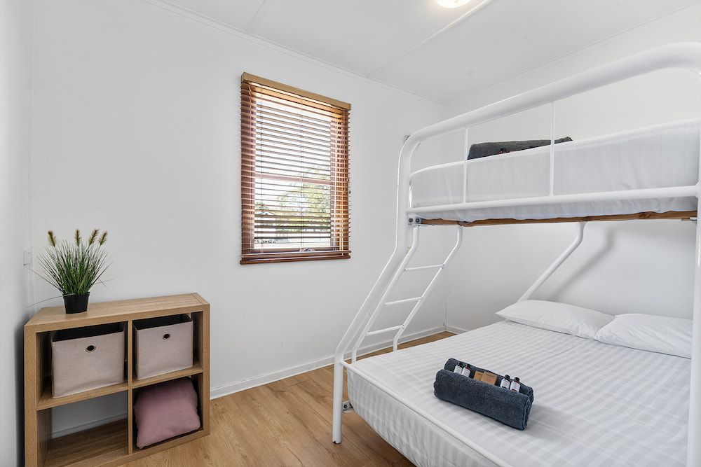 Bedroom With a Bunk Bed, Wooden Blinds, Storage Cubes, and a Small Plant — SeaChange Parks Milton in Milton, NSW