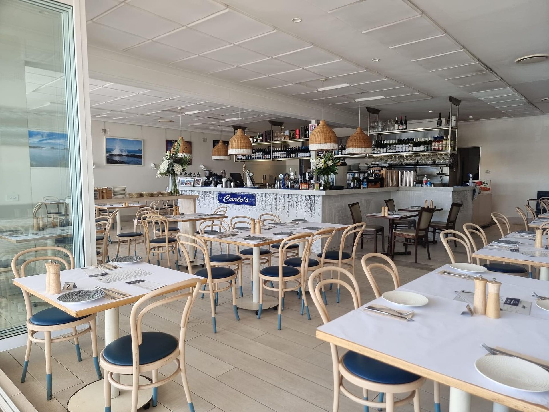 Restaurant Interior With Patrons Dining, Open to a Balcony With a Scenic View and a Palm Tree — SeaChange Parks Milton in Milton, NSW