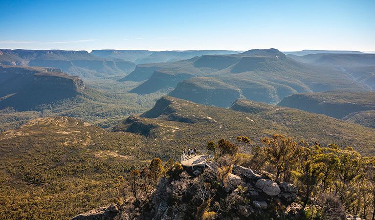 Wide-angle view of a vast, forested canyon landscape with rugged sandstone cliffs under a clear blue sky  — SeaChange Parks Milton in Milton, NSW