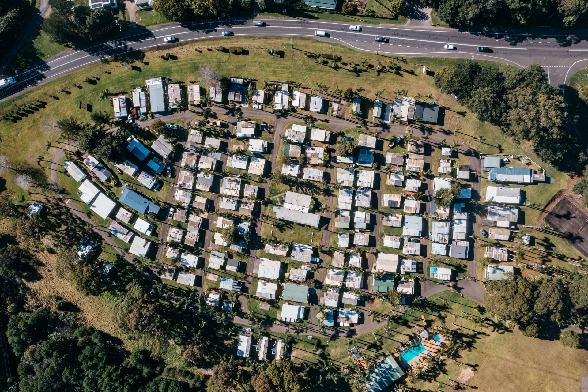 Aerial view of a densely packed mobile home park nestled in a grassy landscape next to a winding road  — SeaChange Parks Milton in Milton, NSW