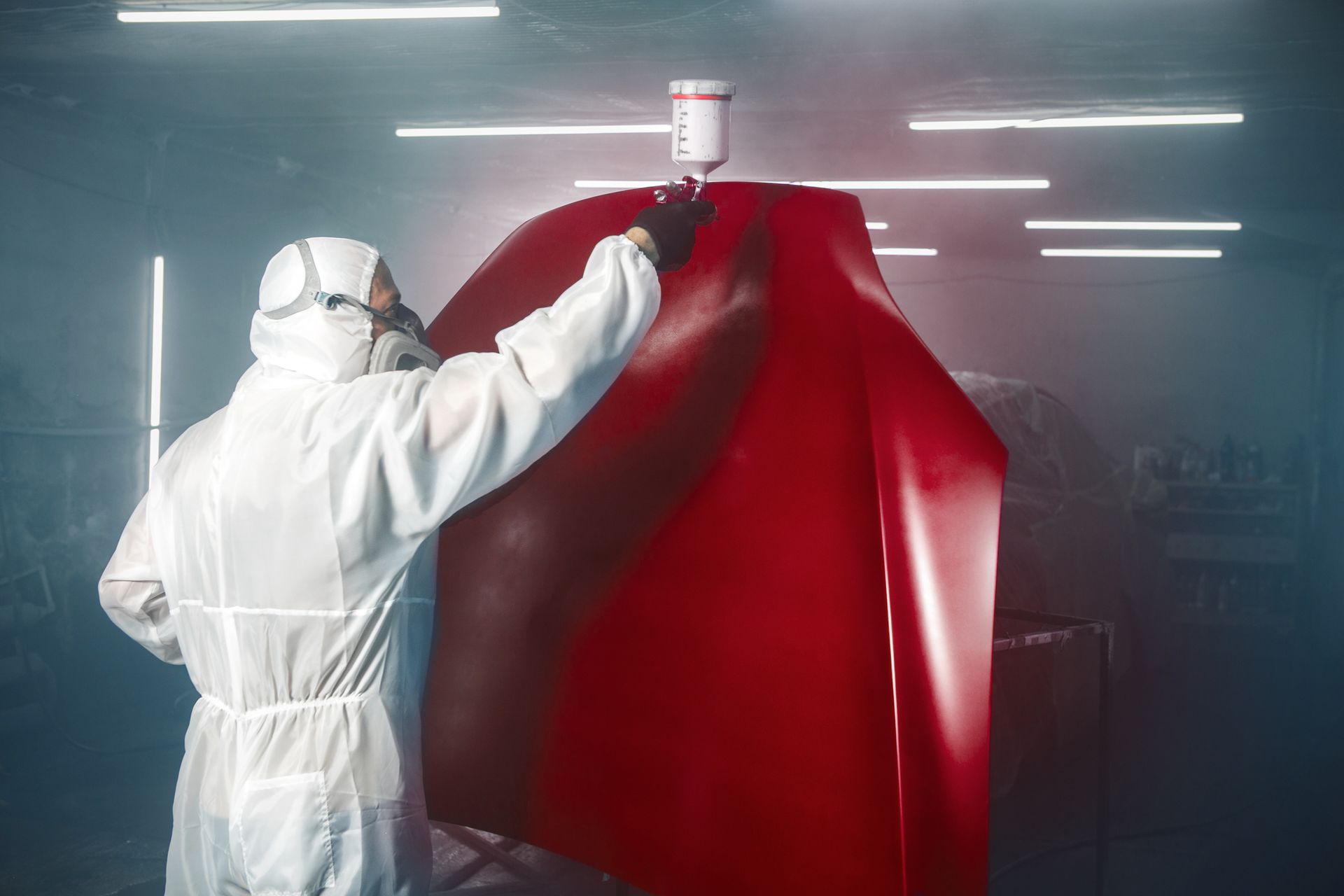 Car painter spraying red paint with spray gun on vehicle element in paint chamber | Huonville,TAS Car painter spraying red paint with spray gun on vehicle element in paint chamber | Huonville,TAS