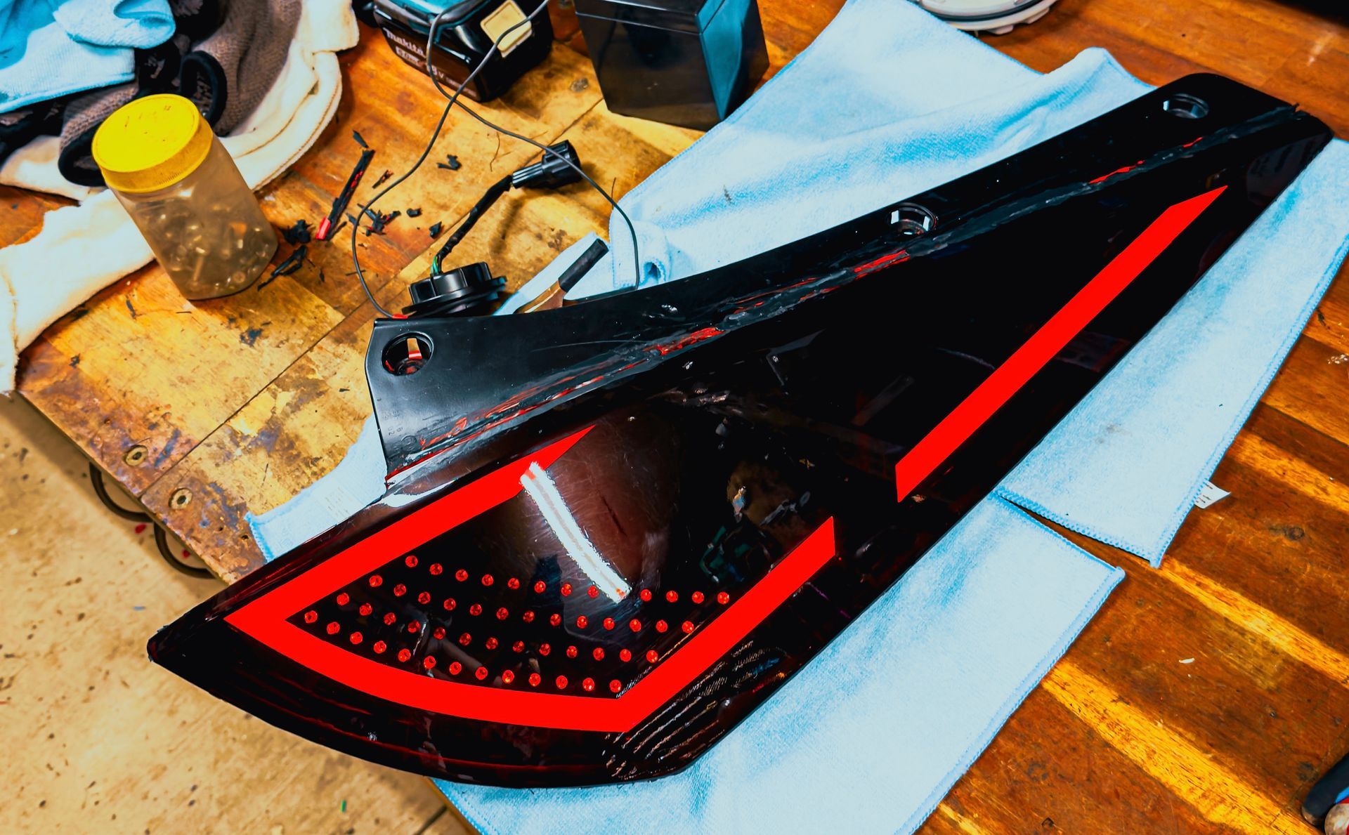 Black car tail light with red LED accents, on a work surface.