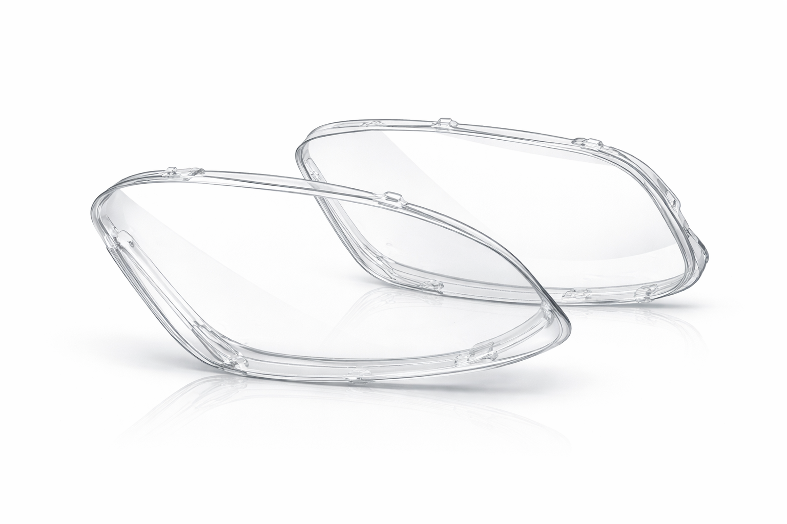 A pair of clear, contoured automotive headlight lens covers against a plain white background.