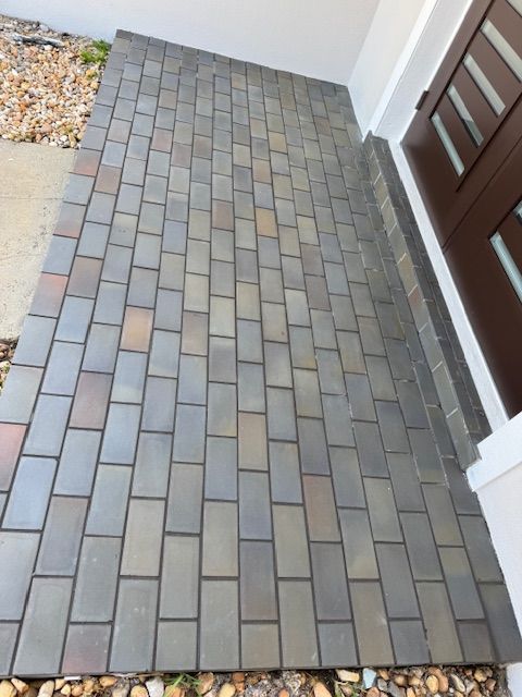A brick walkway leading to a brown door