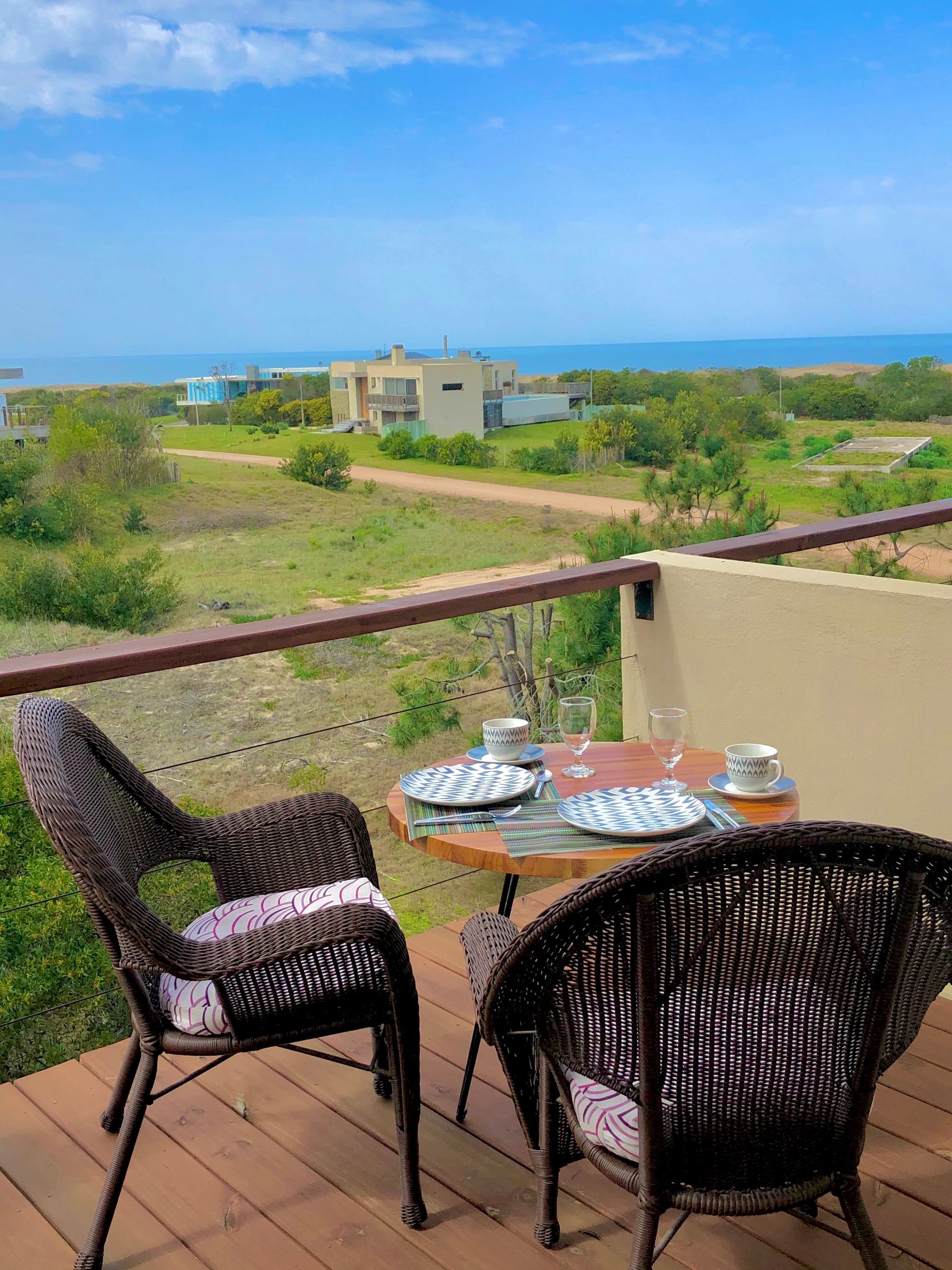 Una mesa y sillas en un balcón con vista al mar.