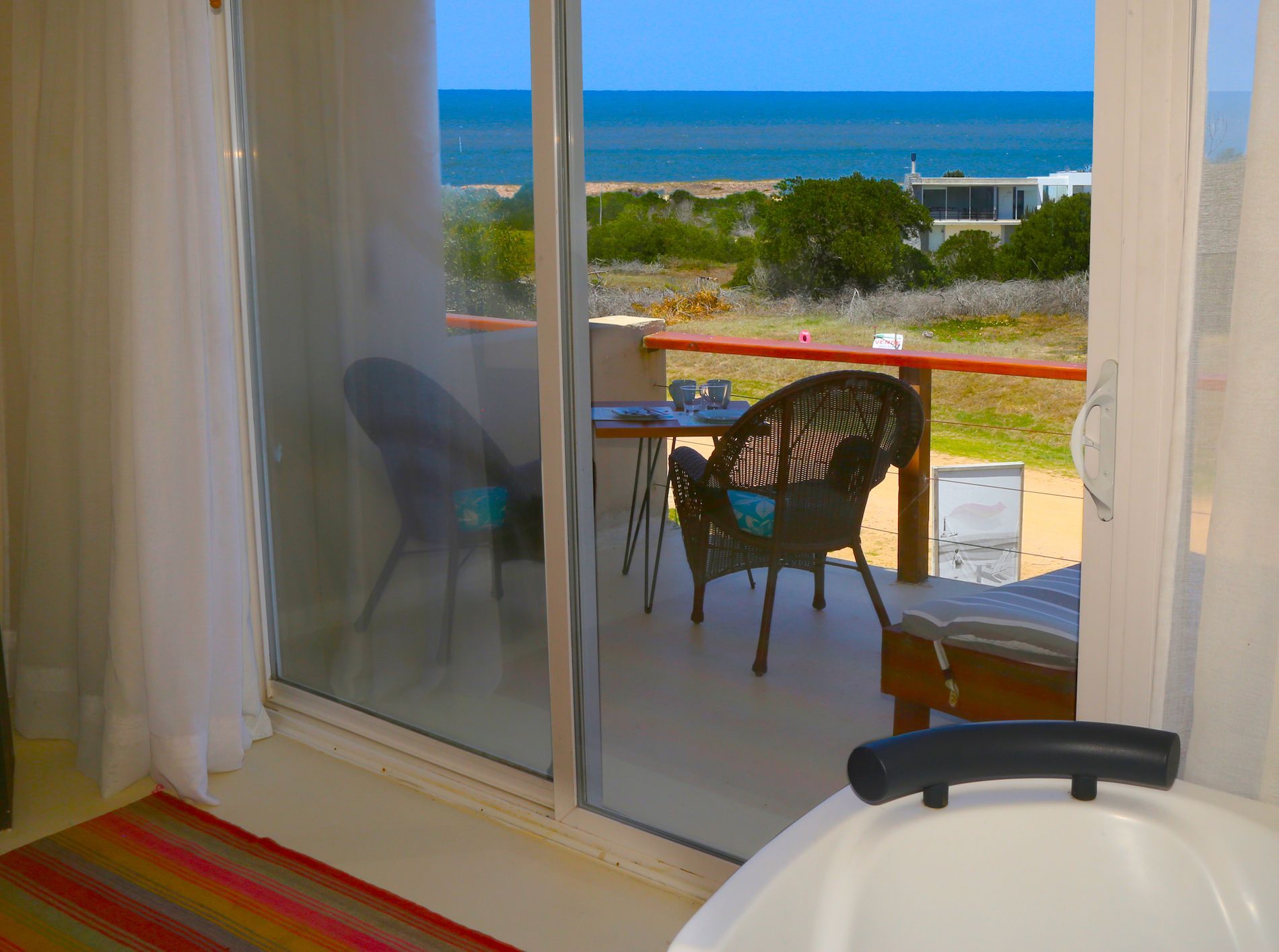 Un baño con bañera y vista al mar.