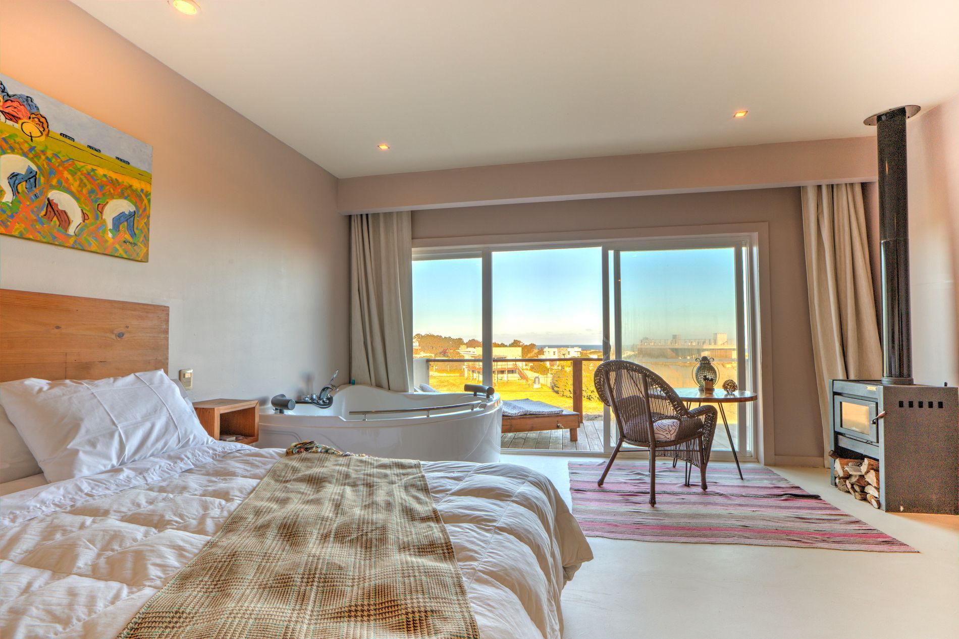 Una habitación de hotel con una cama grande, silla, mesa y puertas corredizas de vidrio.