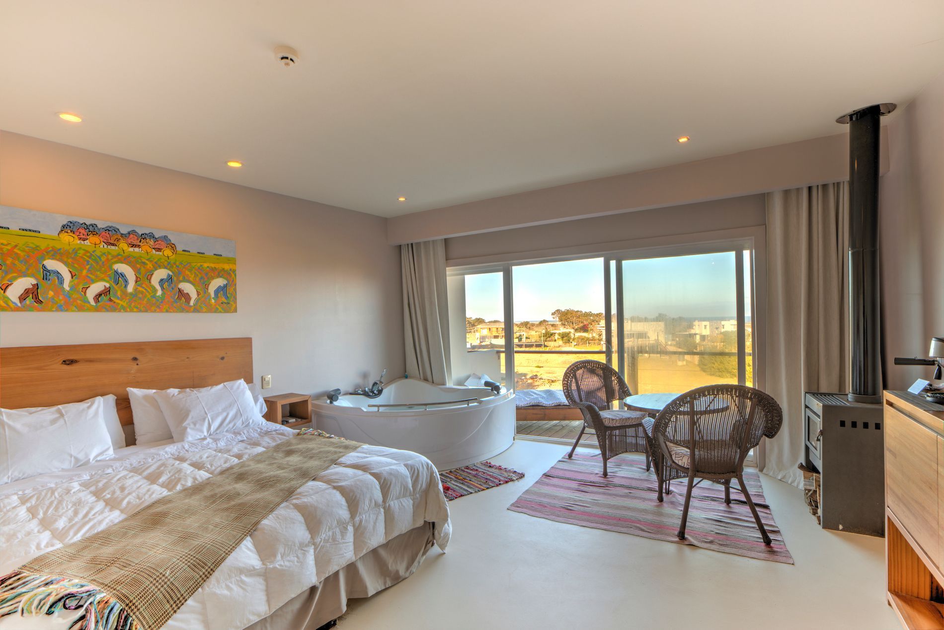 Una habitación de hotel con una cama grande, sillas y una bañera de hidromasaje.