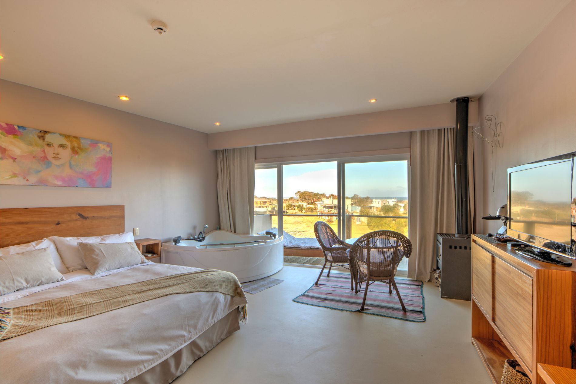 Una habitación de hotel con una cama grande, televisión, sillas y una bañera.