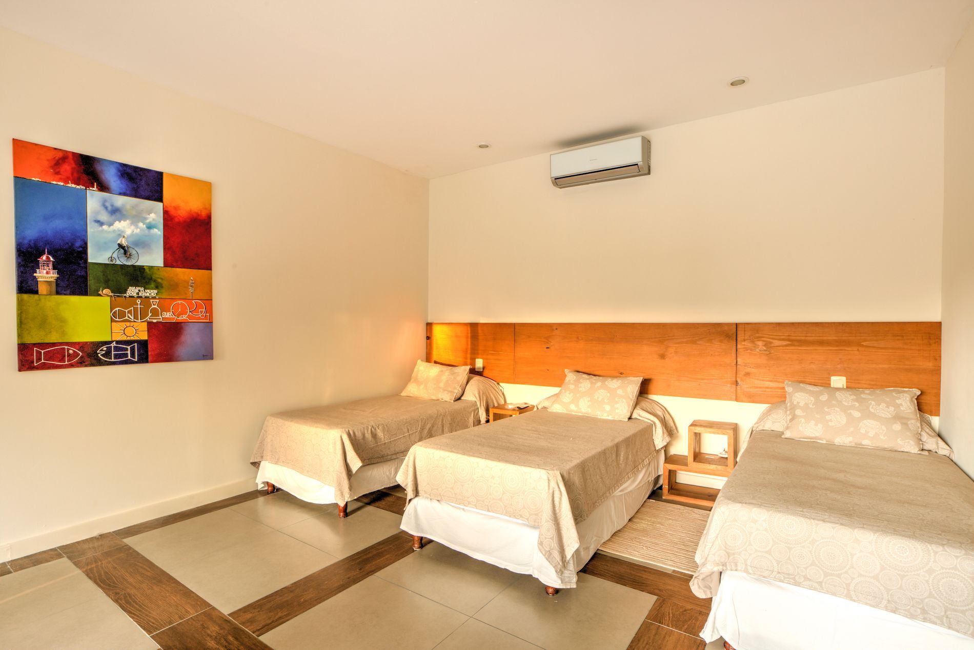 Un dormitorio con tres camas y un cuadro en la pared.