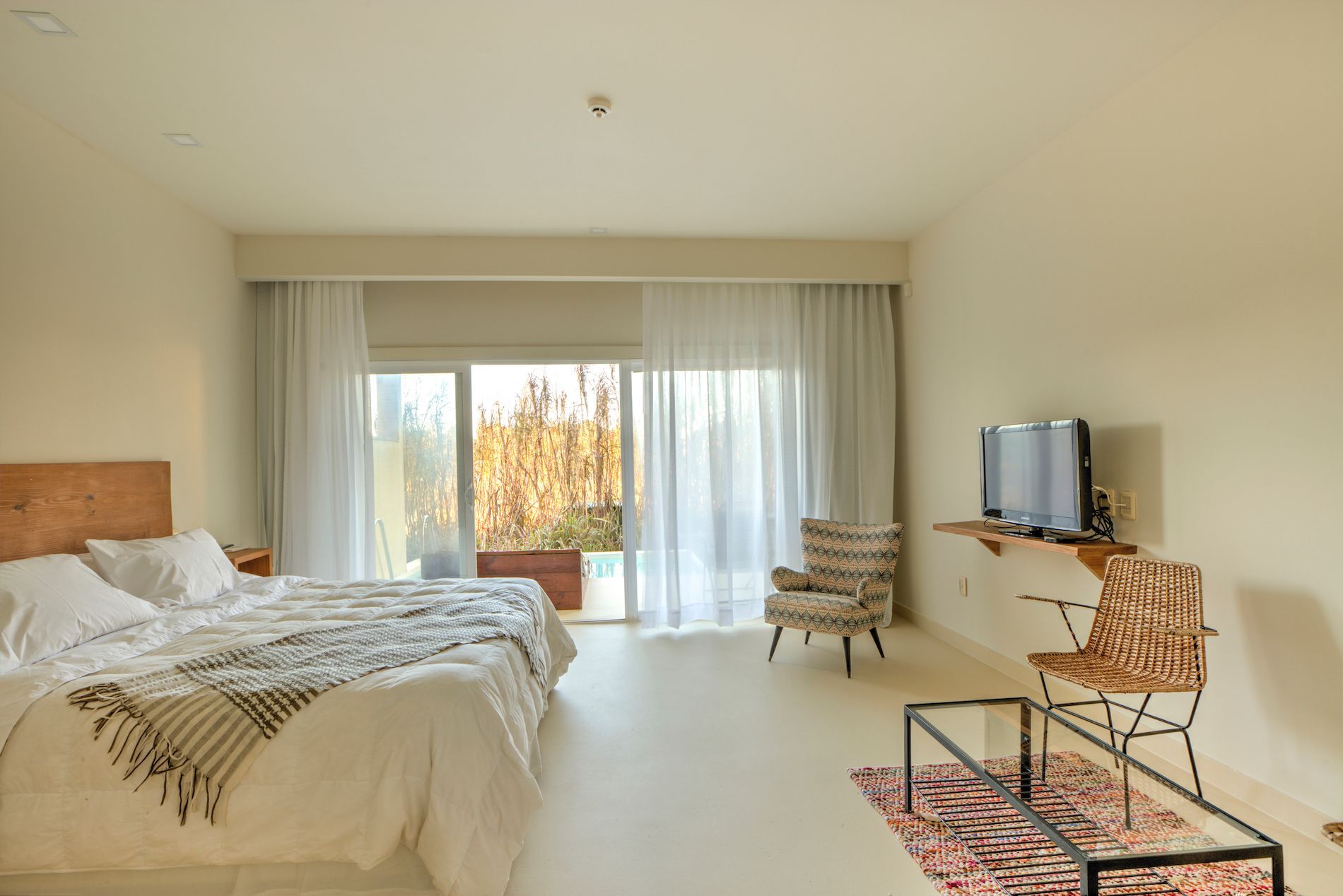 Una habitación de hotel con dos camas, una silla, una mesa y un televisor.