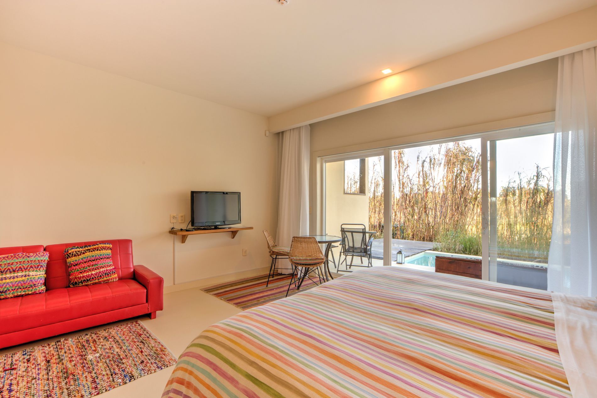 Un dormitorio con cama, sofá, televisión y puertas corredizas de vidrio.