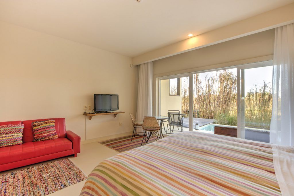 Un dormitorio con cama, sofá, televisión y una gran ventana.