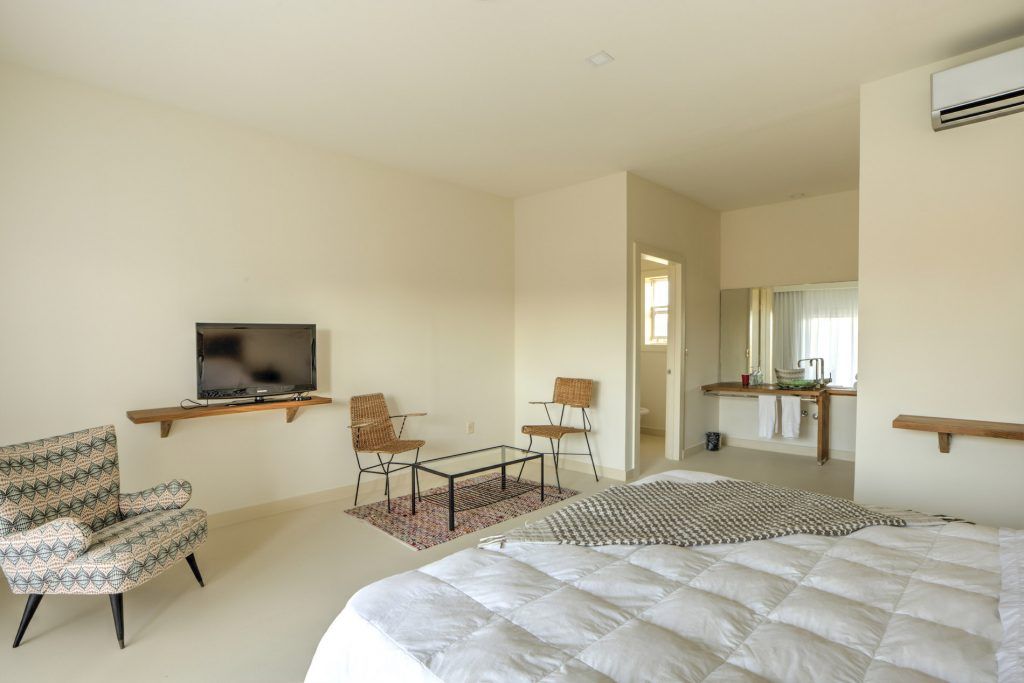 Un dormitorio con cama, sillas, mesa y televisión.