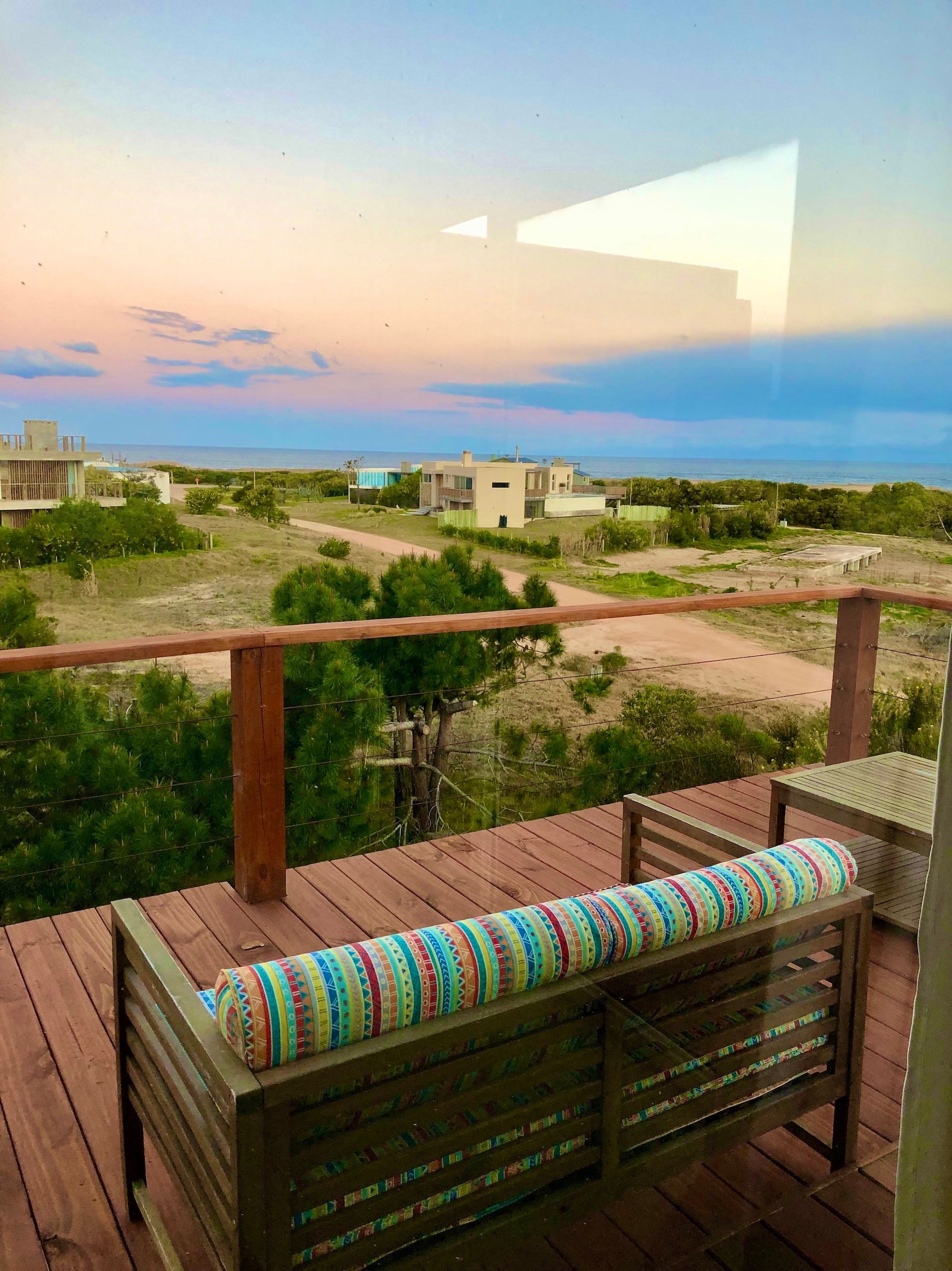 Una terraza de madera con un sofá y sillas y vista al océano.