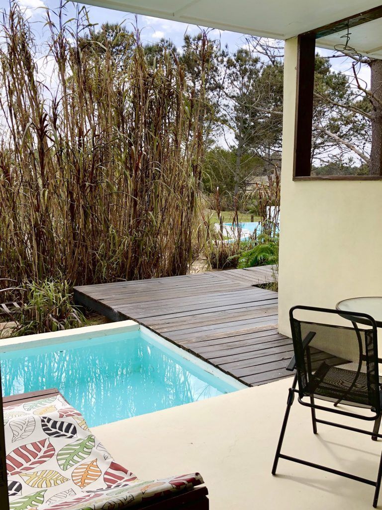 Un patio con mesa y sillas al lado de una piscina.