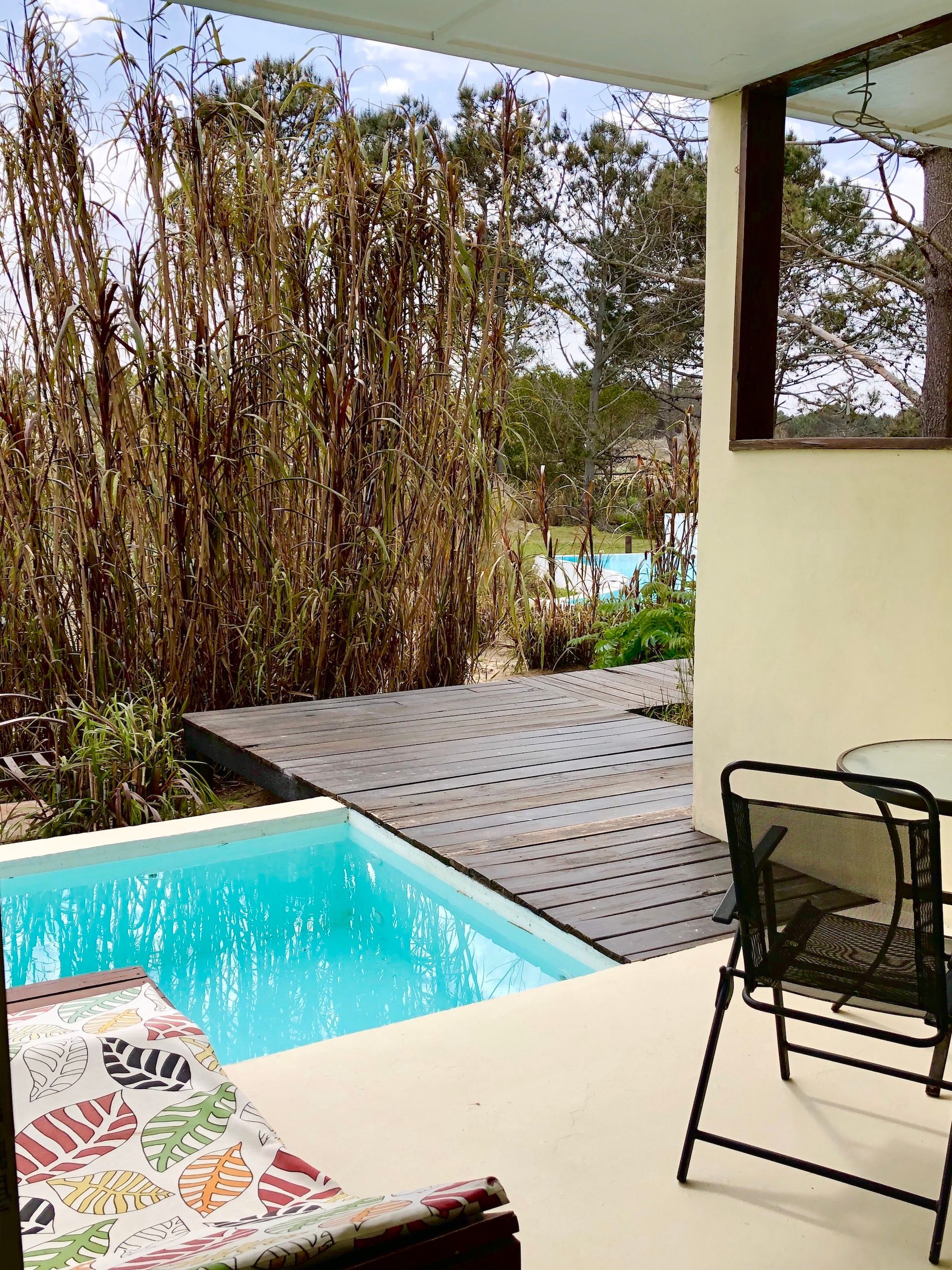 Un patio con mesa y sillas al lado de una piscina.