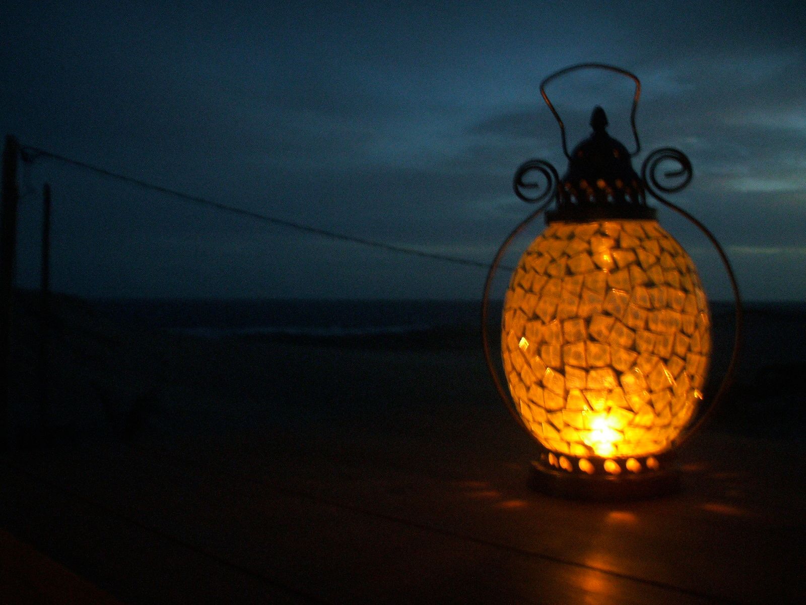 Una linterna se enciende en la oscuridad con el océano de fondo.