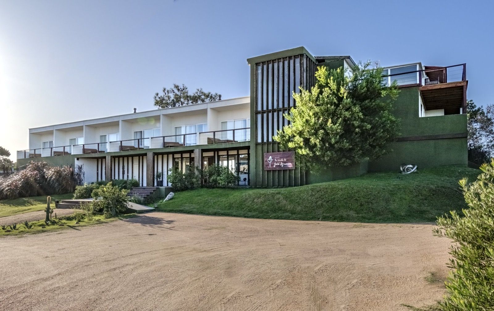 Un gran edificio con muchas ventanas está situado en la cima de una colina cubierta de hierba.