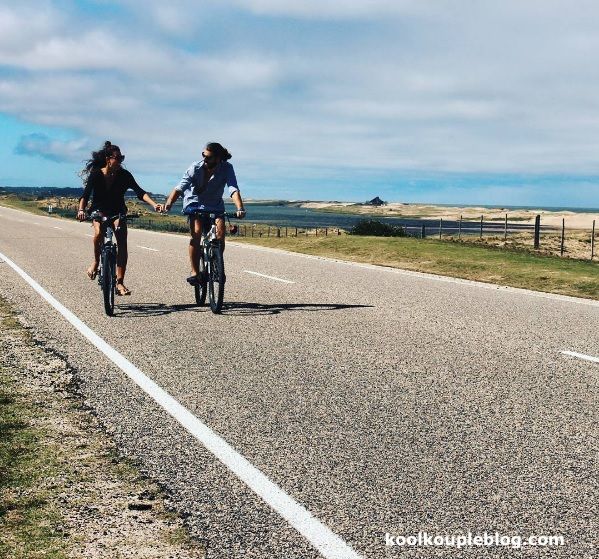 Dos mujeres van en bicicleta por una calle tomadas de la mano