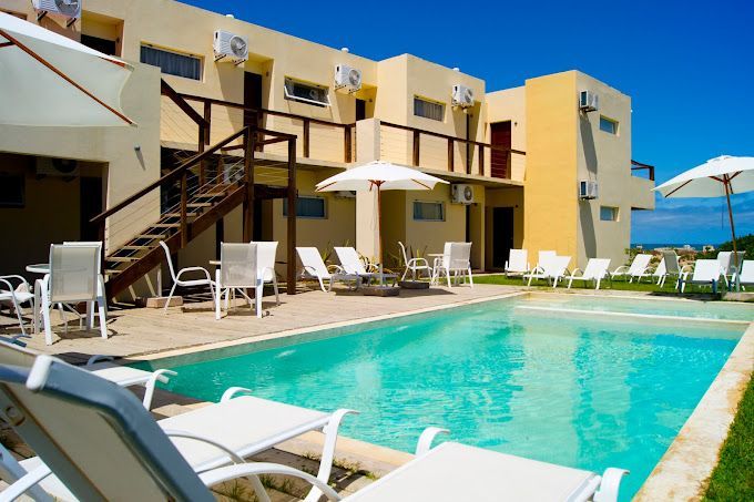 Una piscina con sillas y sombrillas frente a un edificio.