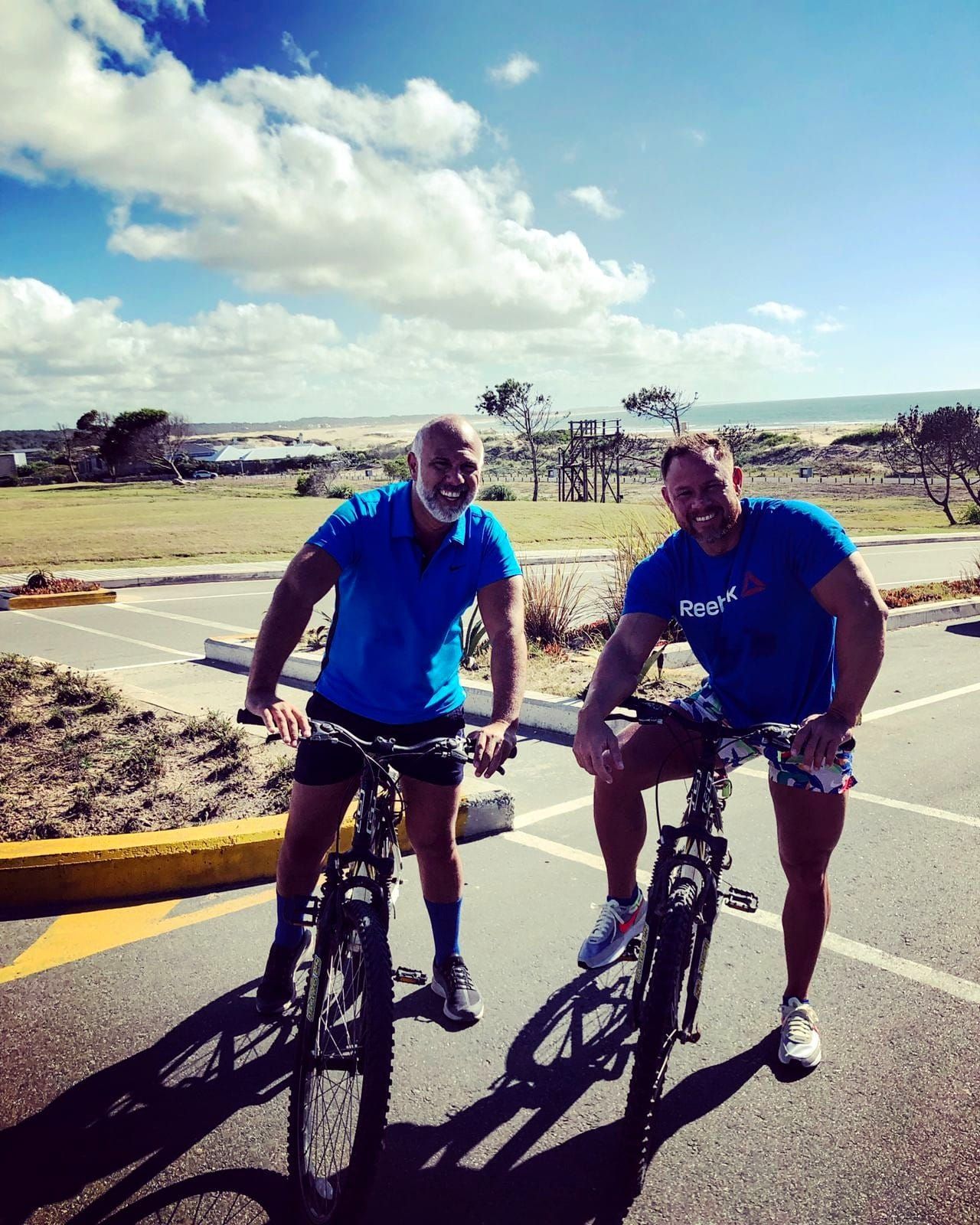 Dos hombres posan para una fotografía mientras andan en bicicleta.