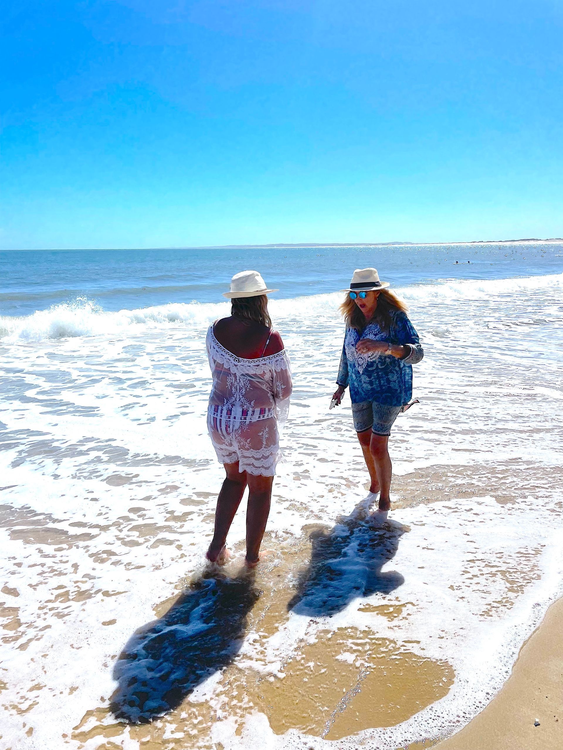 Dos mujeres están paradas en una playa cerca del océano.