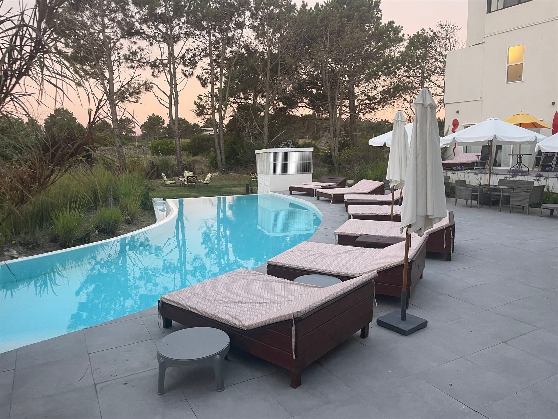 Una fila de tumbonas y sombrillas junto a una piscina.