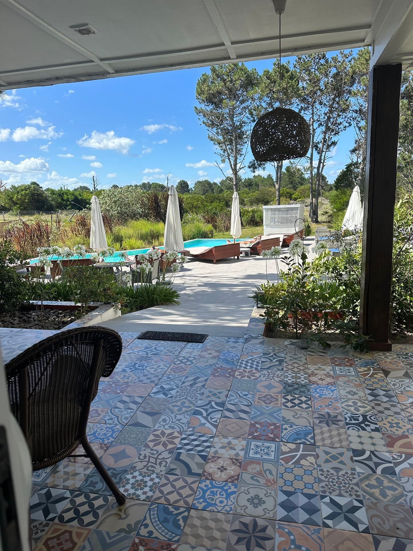 Un patio con una silla de mimbre y una piscina al fondo.