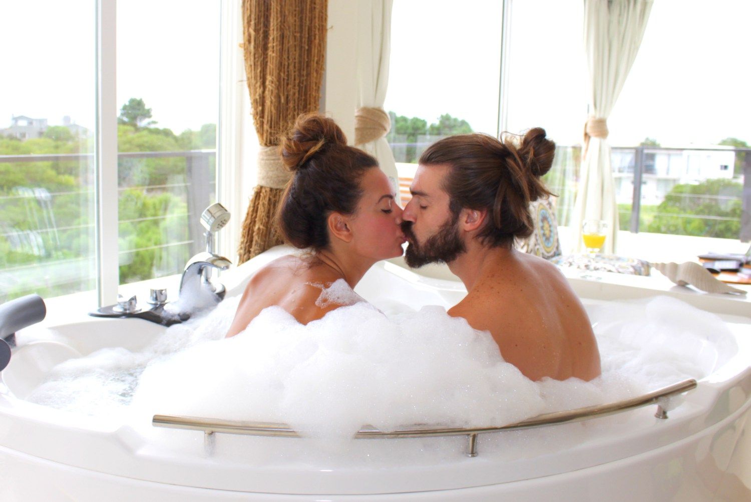 Un hombre y una mujer se besan en una bañera llena de espuma.