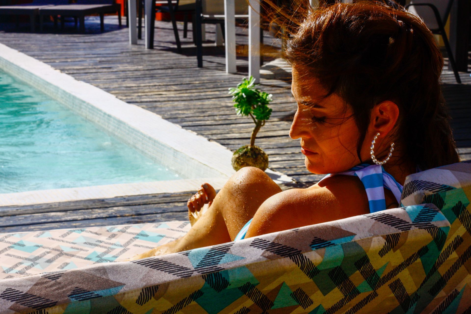 Una mujer está sentada en una silla cerca de una piscina.