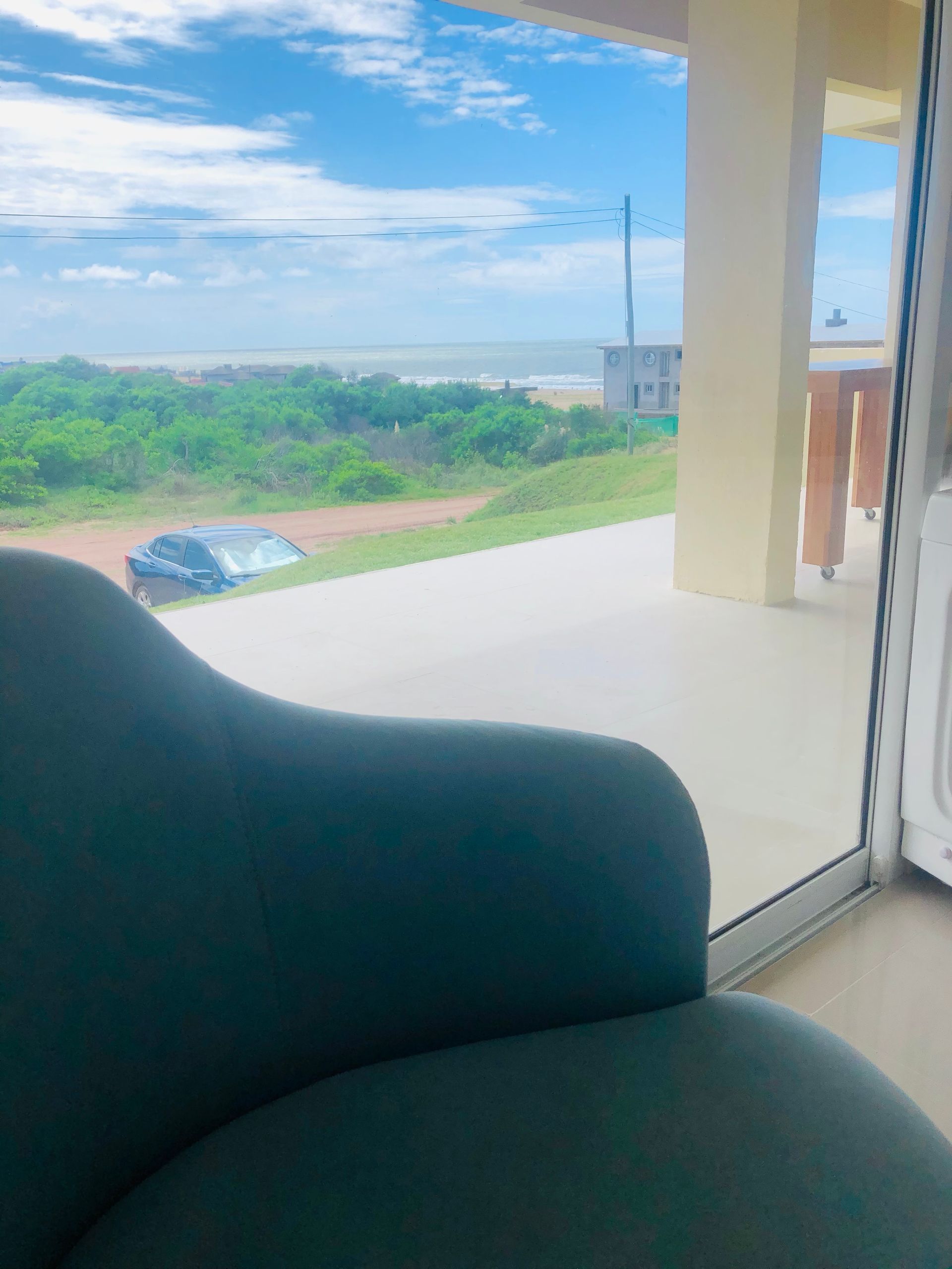 Una silla está sentada frente a una ventana con vista al océano.