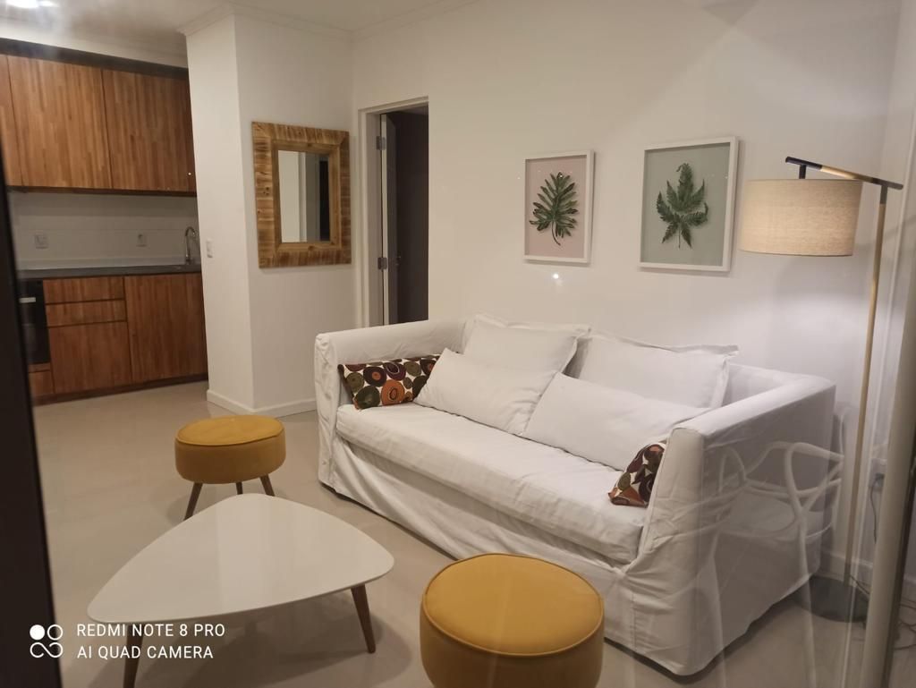 Una sala de estar con un sofá blanco y otomanas amarillas.