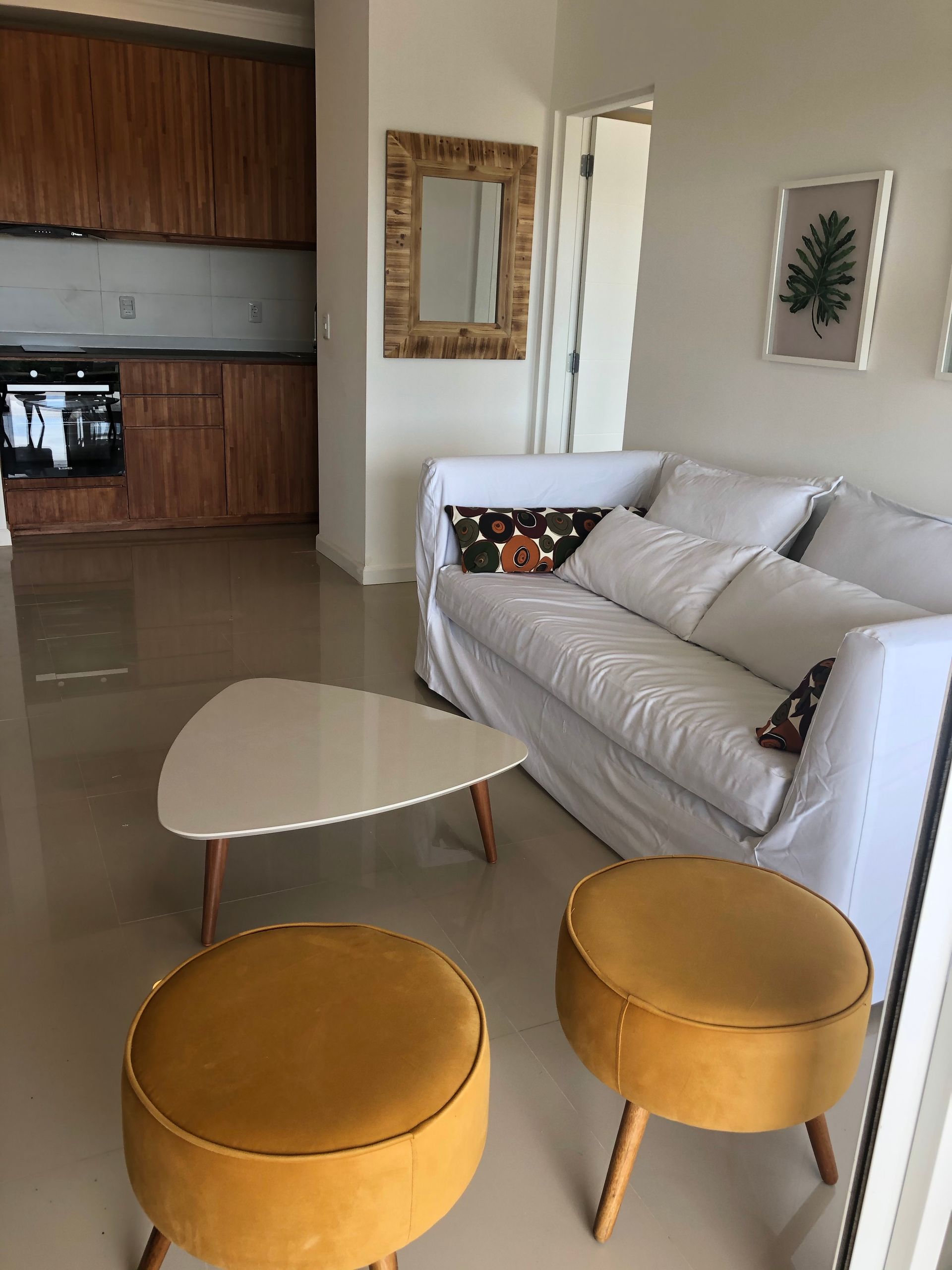 Una sala de estar con un sofá, dos otomanas, una mesa de café y un espejo.