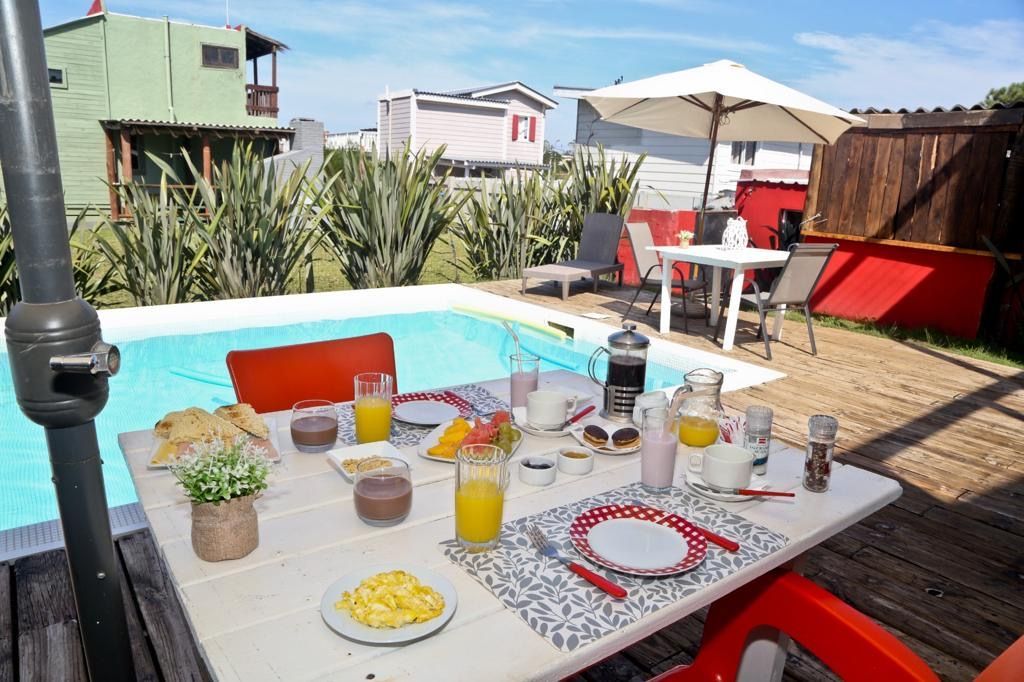 Una mesa con platos de comida y bebidas frente a una piscina.