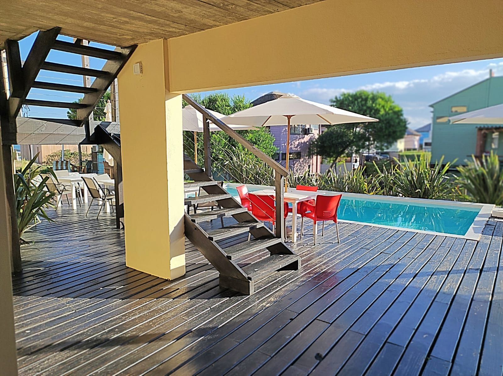 Una terraza de madera con escaleras que conducen a una piscina.