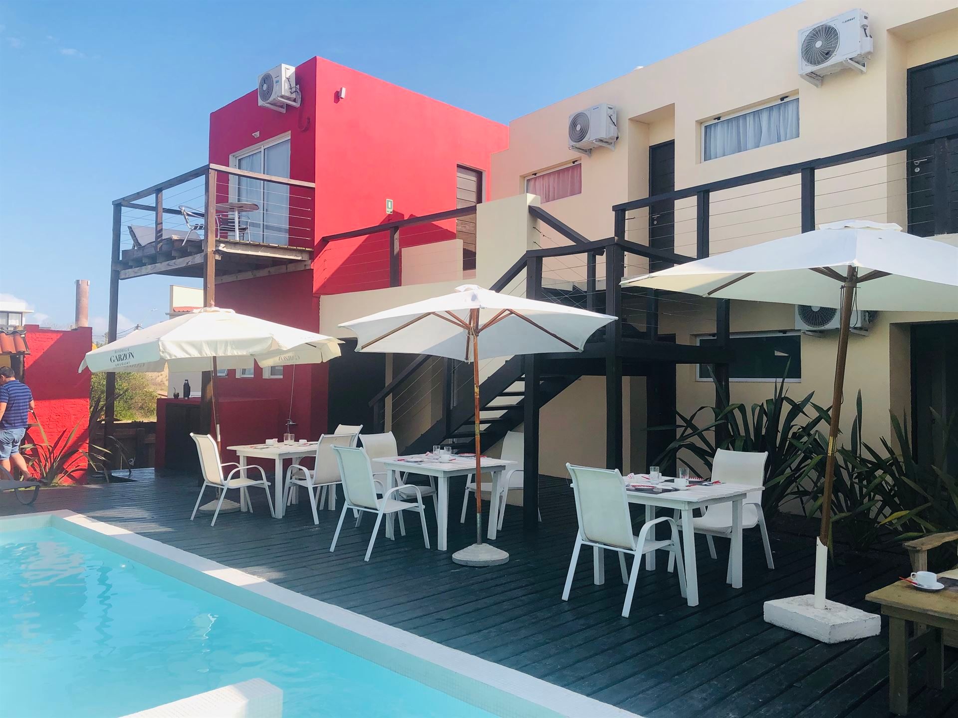 Una piscina con mesas, sillas y sombrillas alrededor.