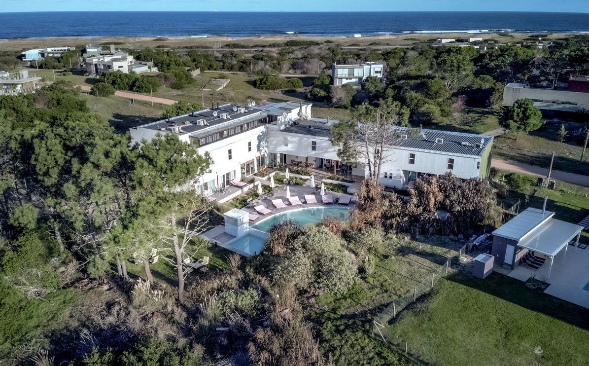 Una vista aérea de una gran casa blanca rodeada de árboles y una piscina.