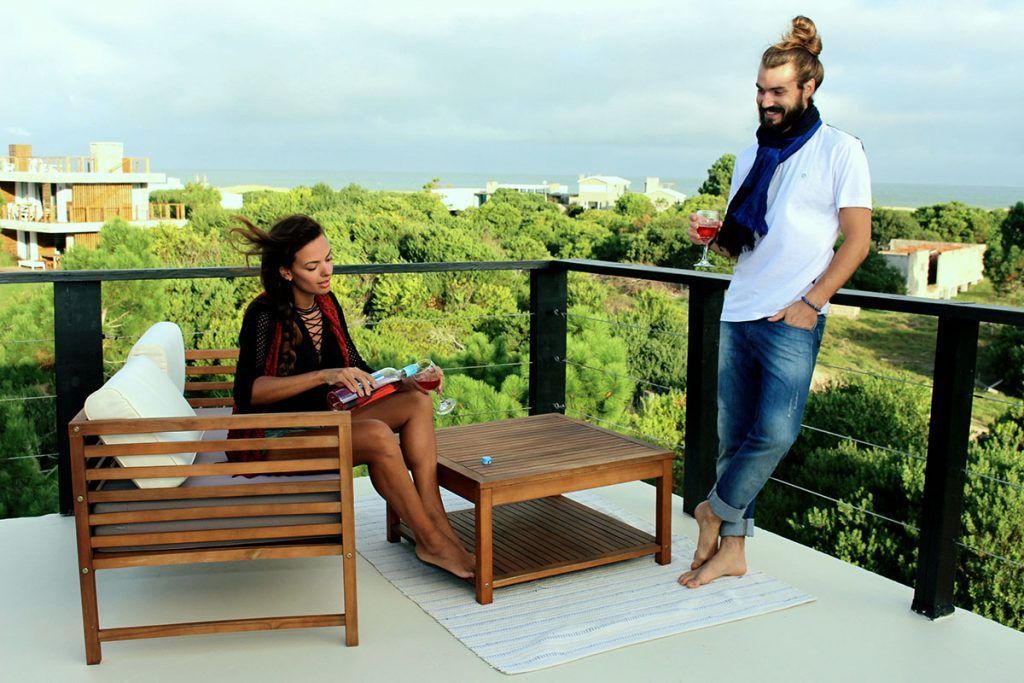 Un hombre de pie junto a una mujer sentada en una silla en un balcón.