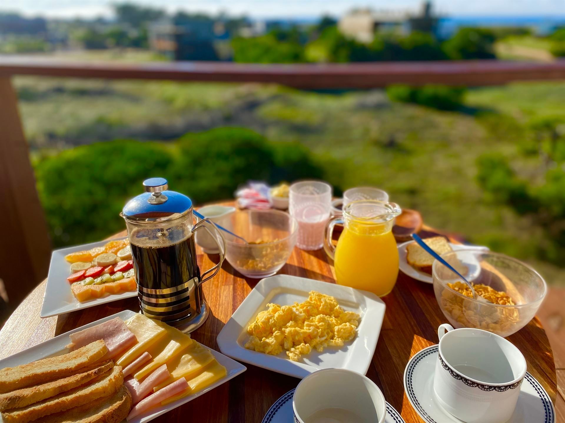 Una mesa cubierta con platos de comida y bebidas con vista al océano.