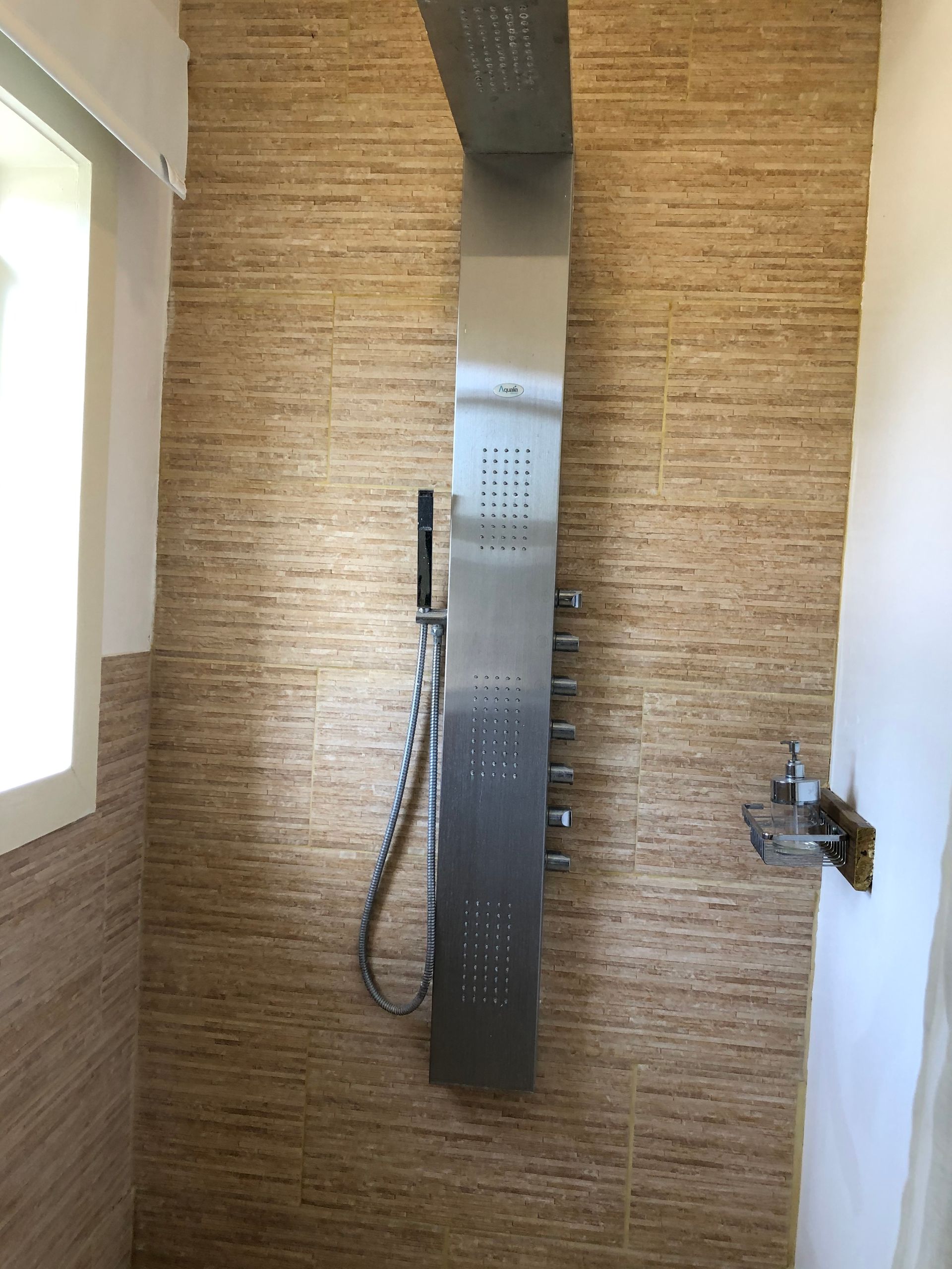 Una ducha con cabezal de ducha de acero inoxidable y ventana.