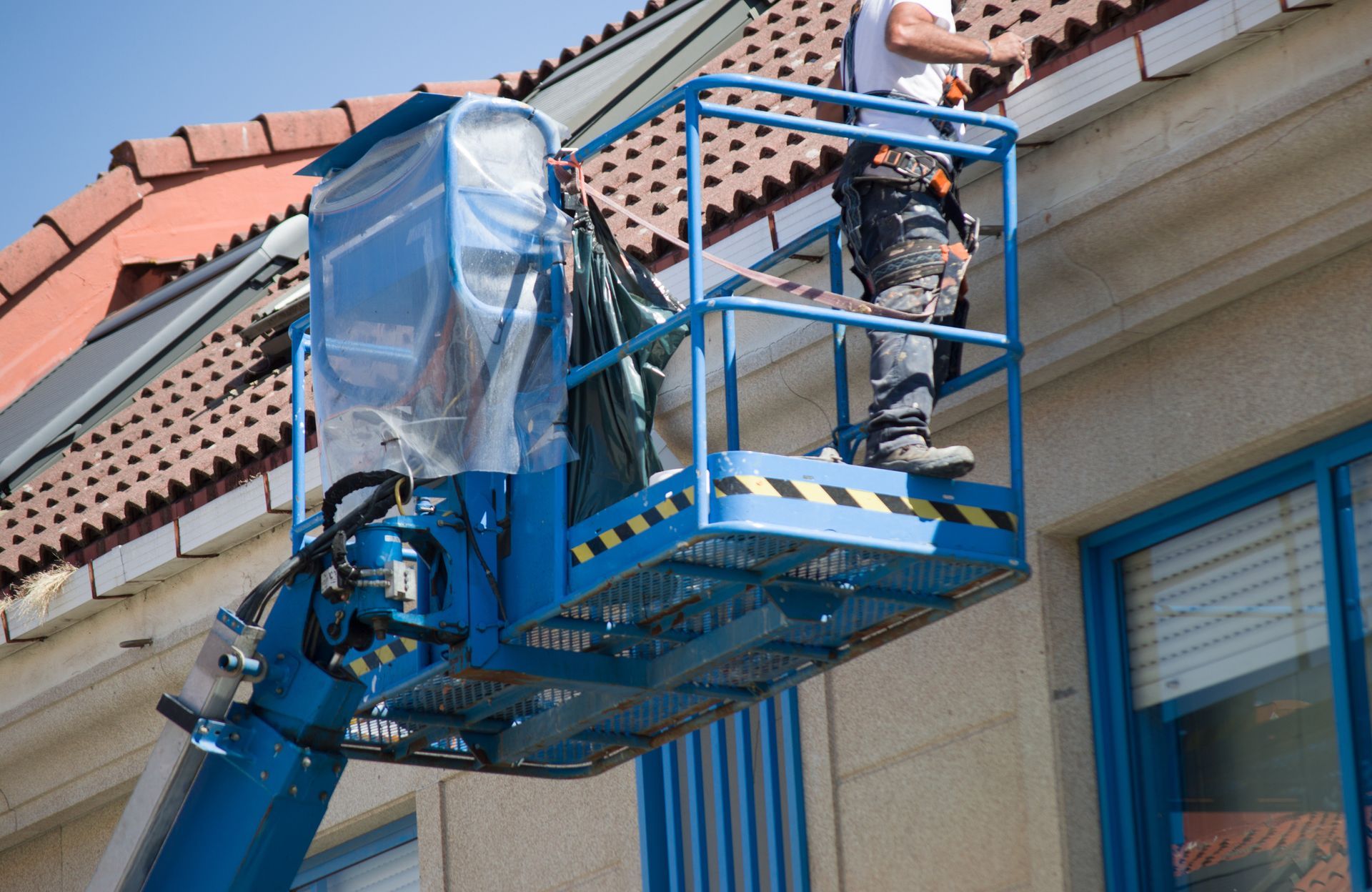 A man is working on the roof of a building on a lift.